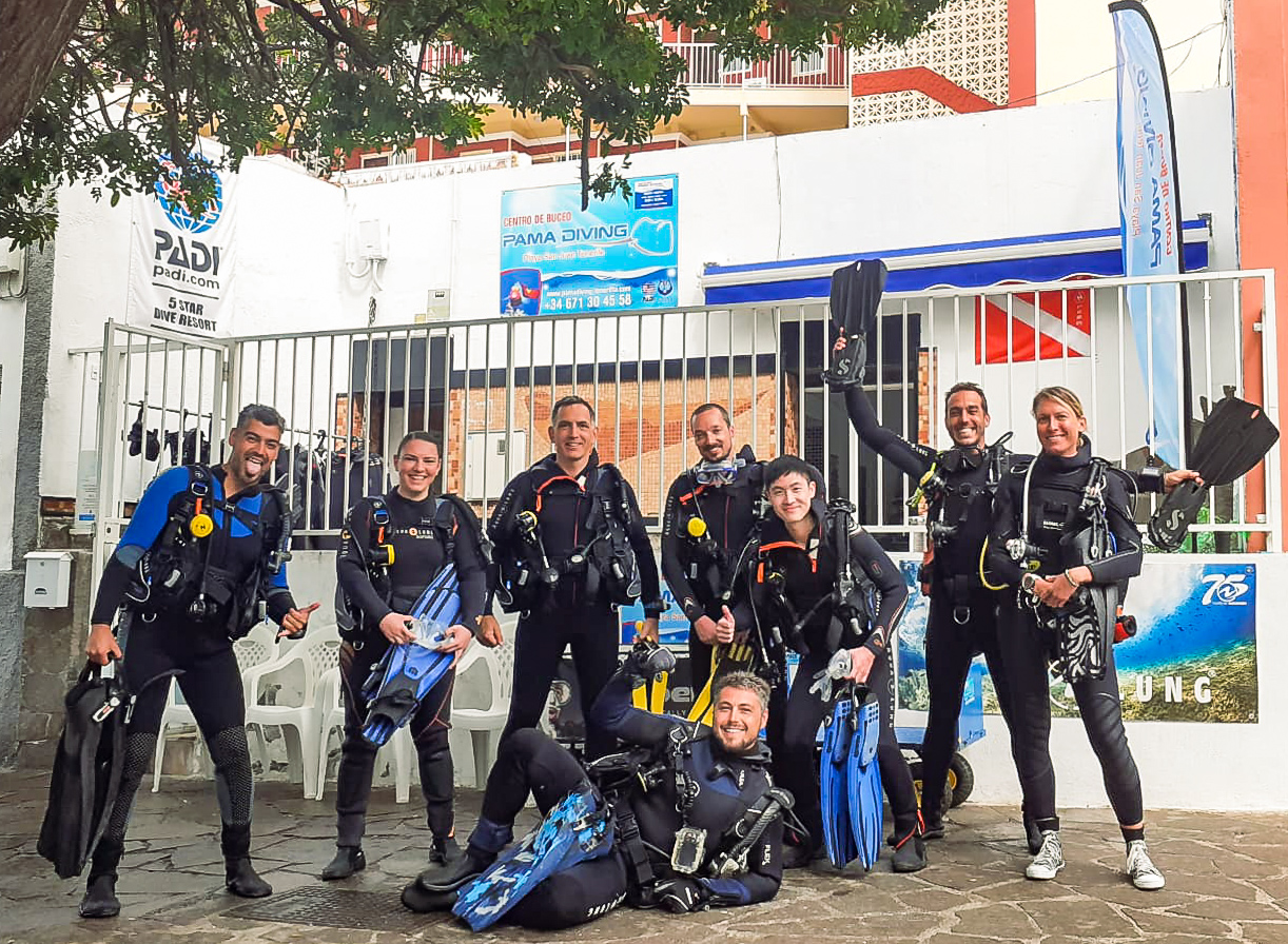 MUI team members and their diving instructors pose in scuba gear before a successful scuba diving lesson.