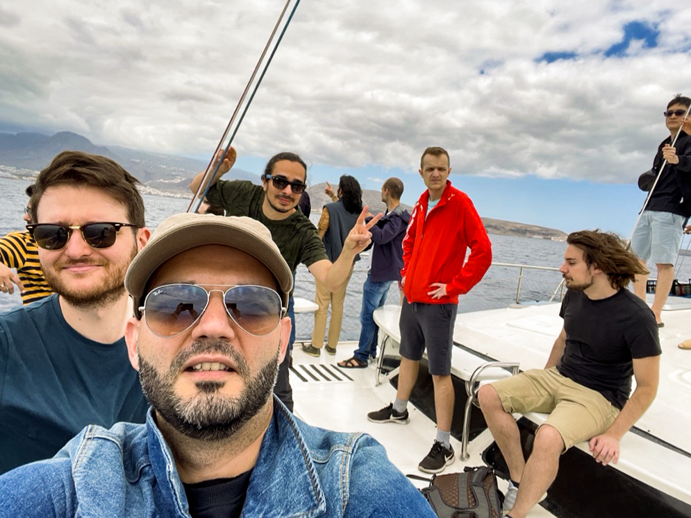 Danail from the MUI X team snaps a selfie on the bow of the whale-watching boat, with coworkers in the background.
