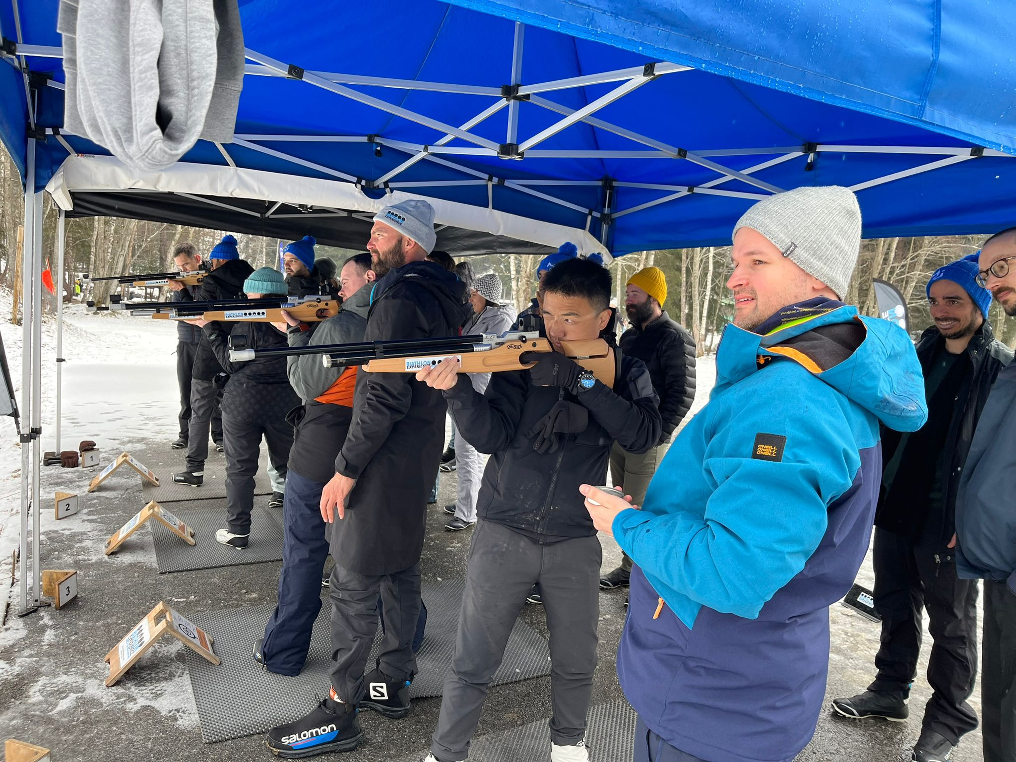 MUI team members standing in a line shooting air rifles as part of a biathlon competition.