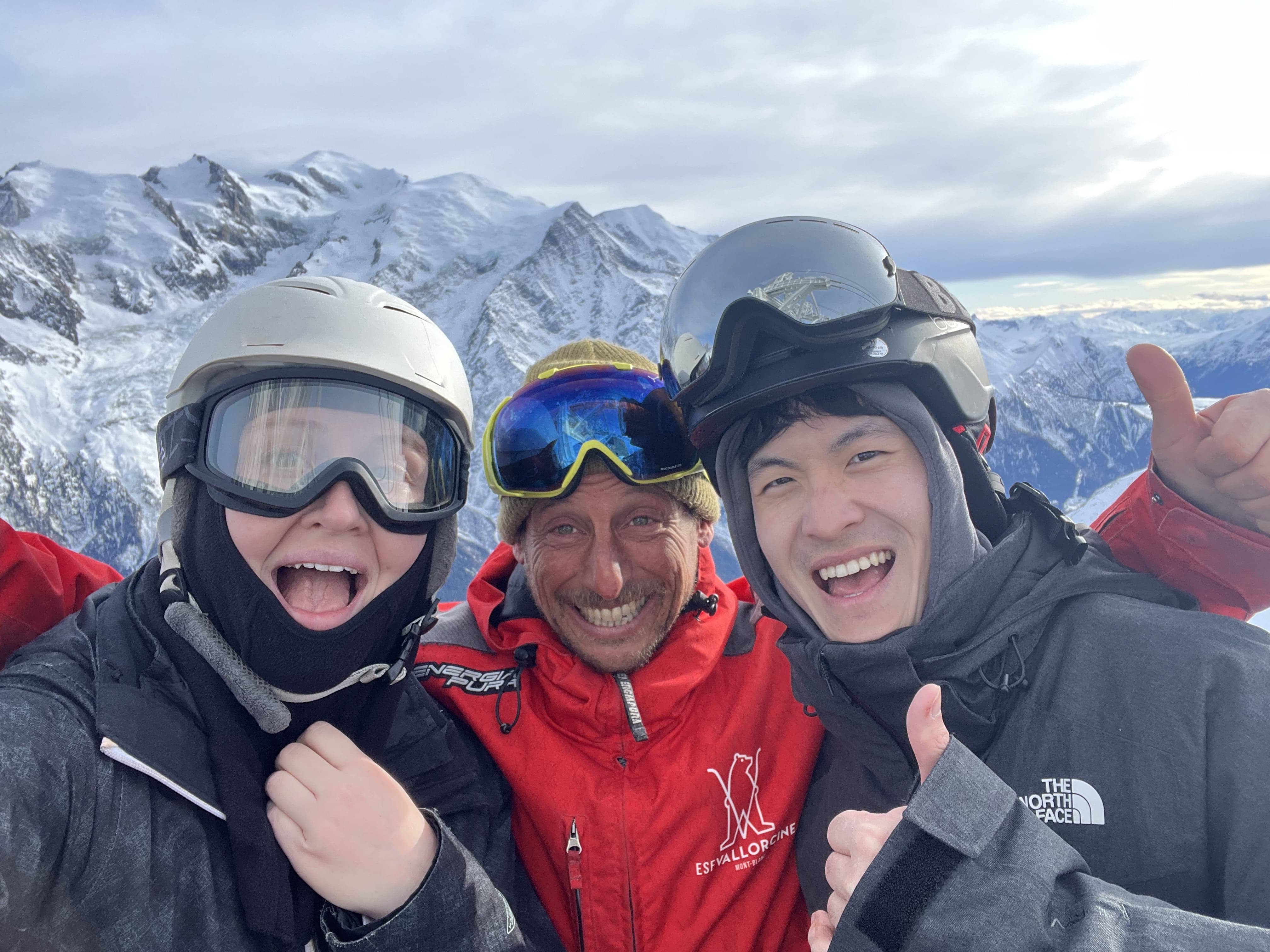 Two members of the MUI team and skiing instructor smiling with a mountain vista in the background.