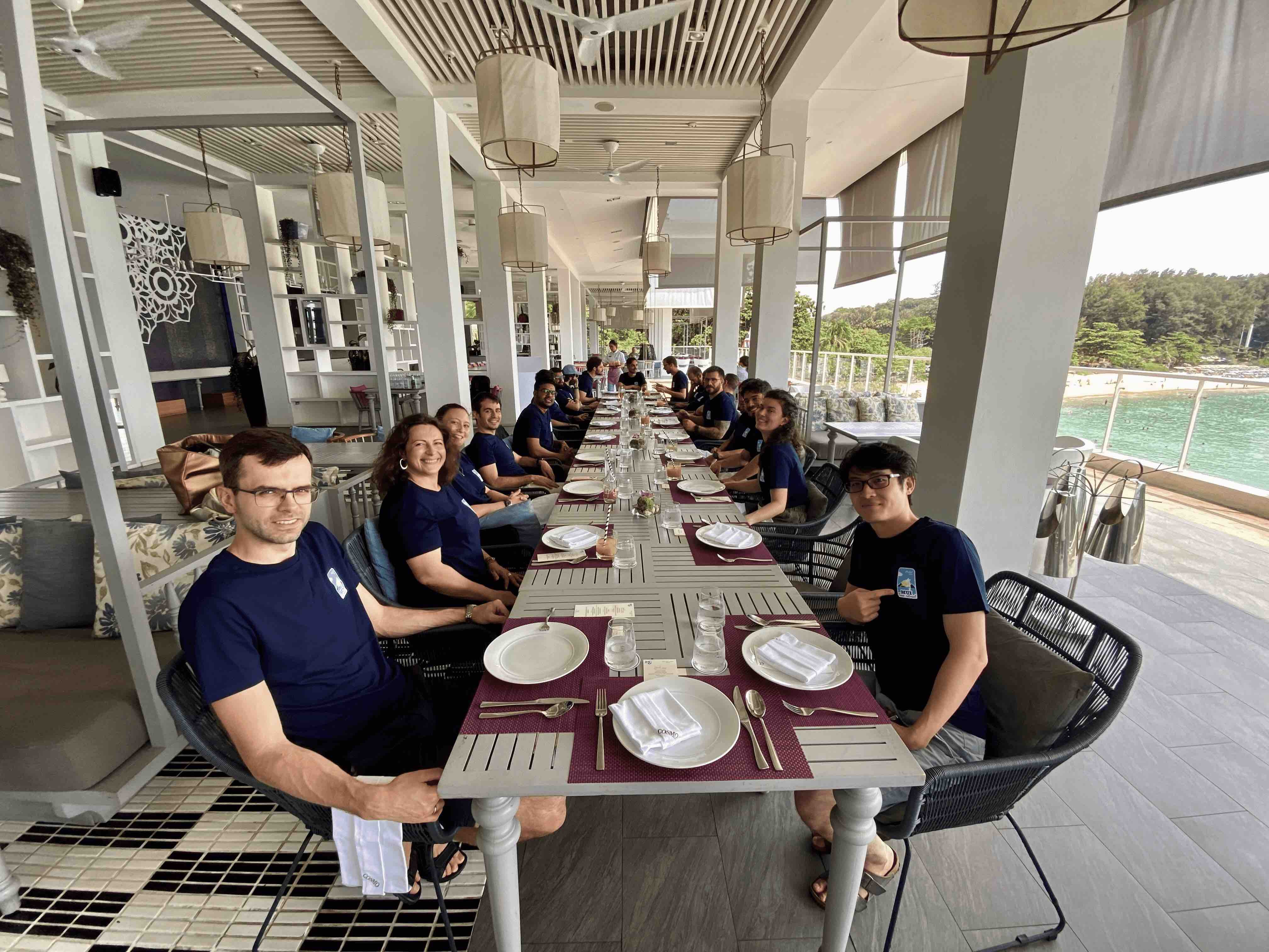 MUI team members seated for a team lunch on the Nai Harn's Cosmo dining hall terrace.